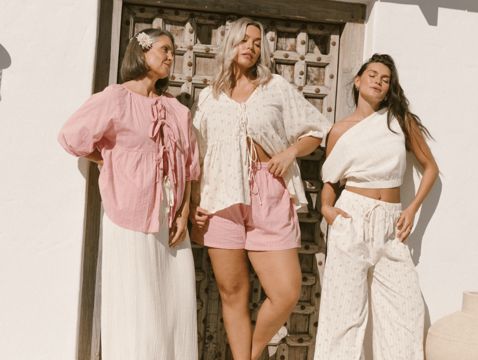 Three women wearing linen printed sets, relaxed sitting on stairs outside in a fashionable manner