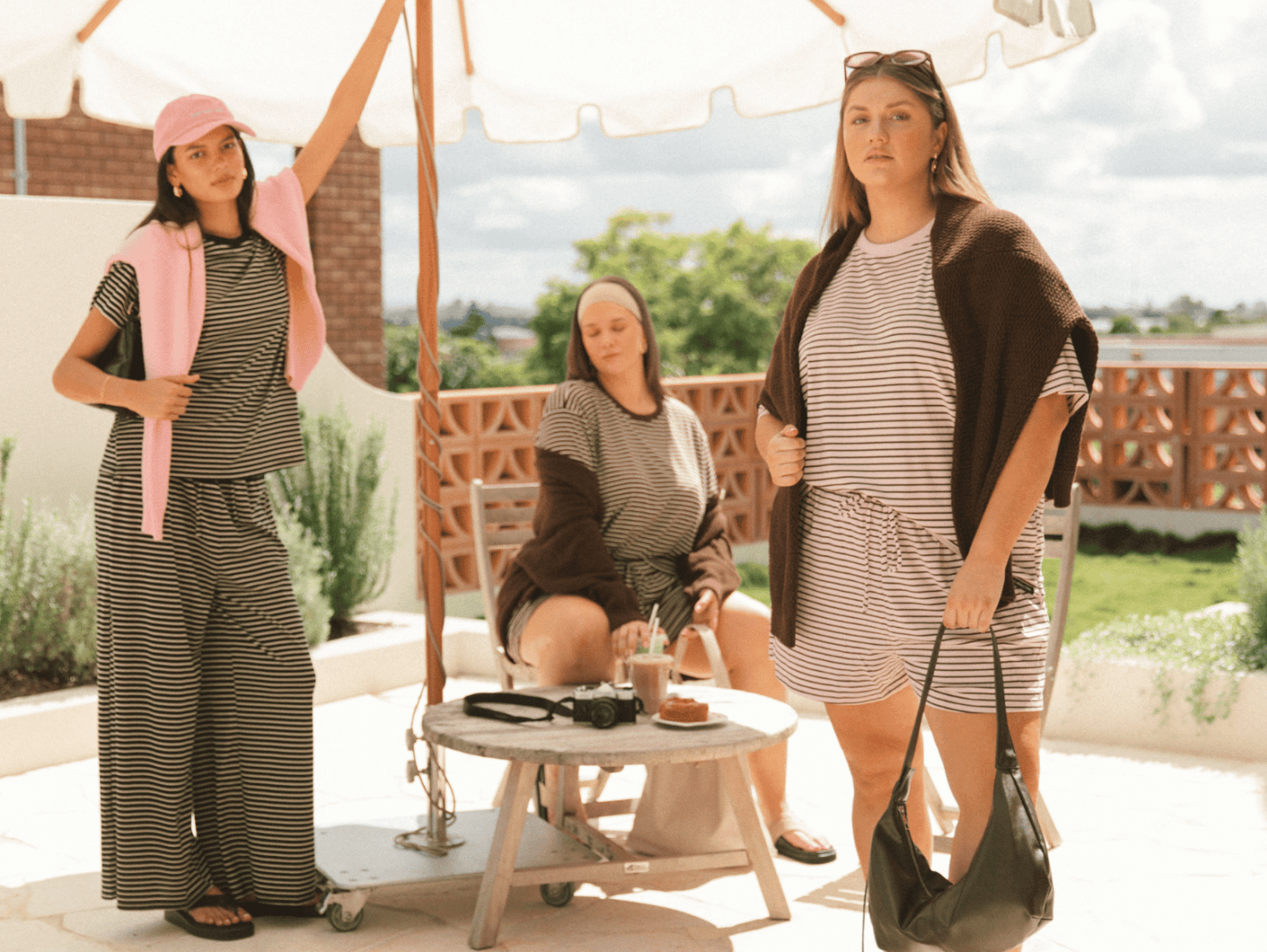 Three women wearing linen printed sets, relaxed sitting on stairs outside in a fashionable manner