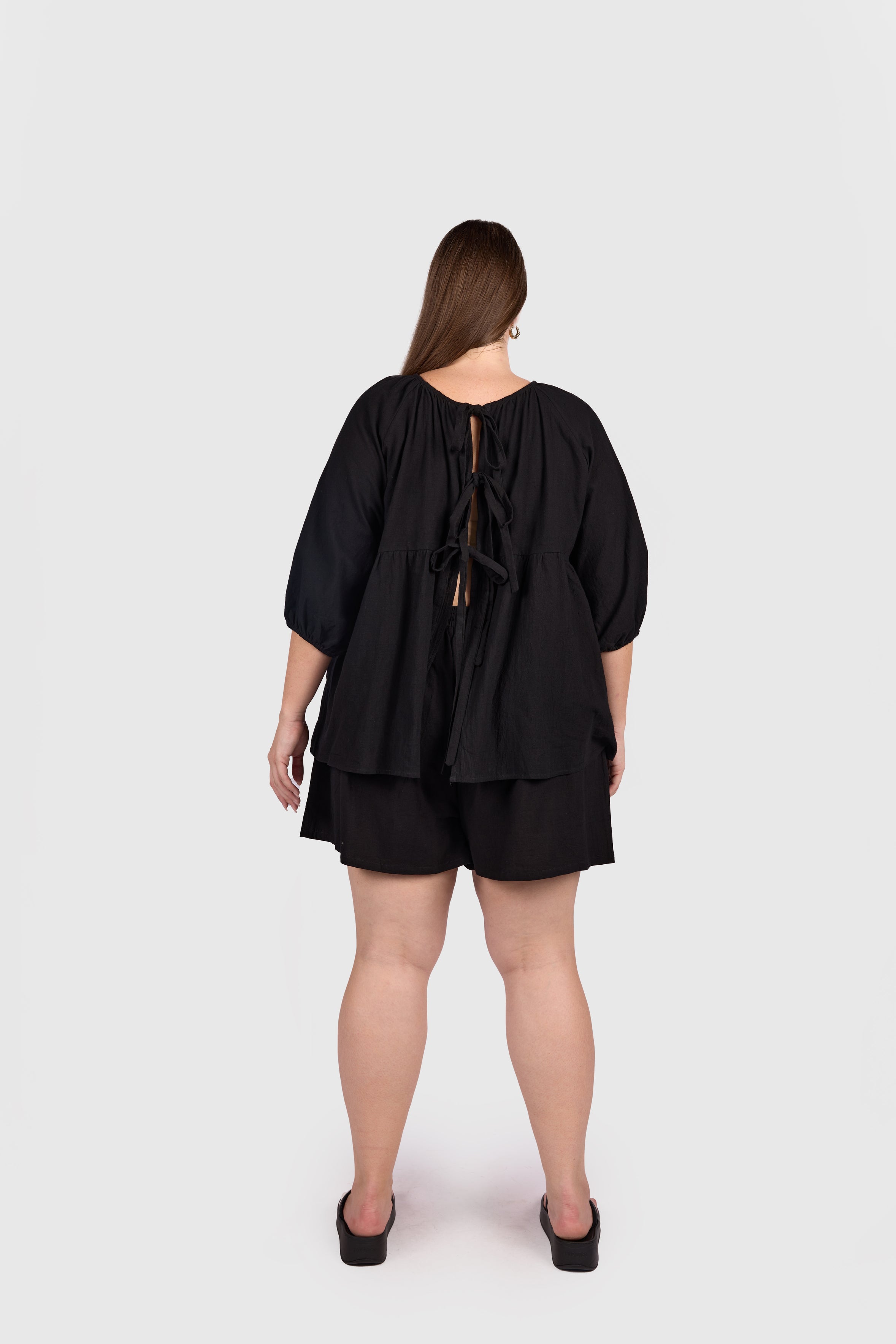 Woman wearing reversible black cotton top with tie up back.
