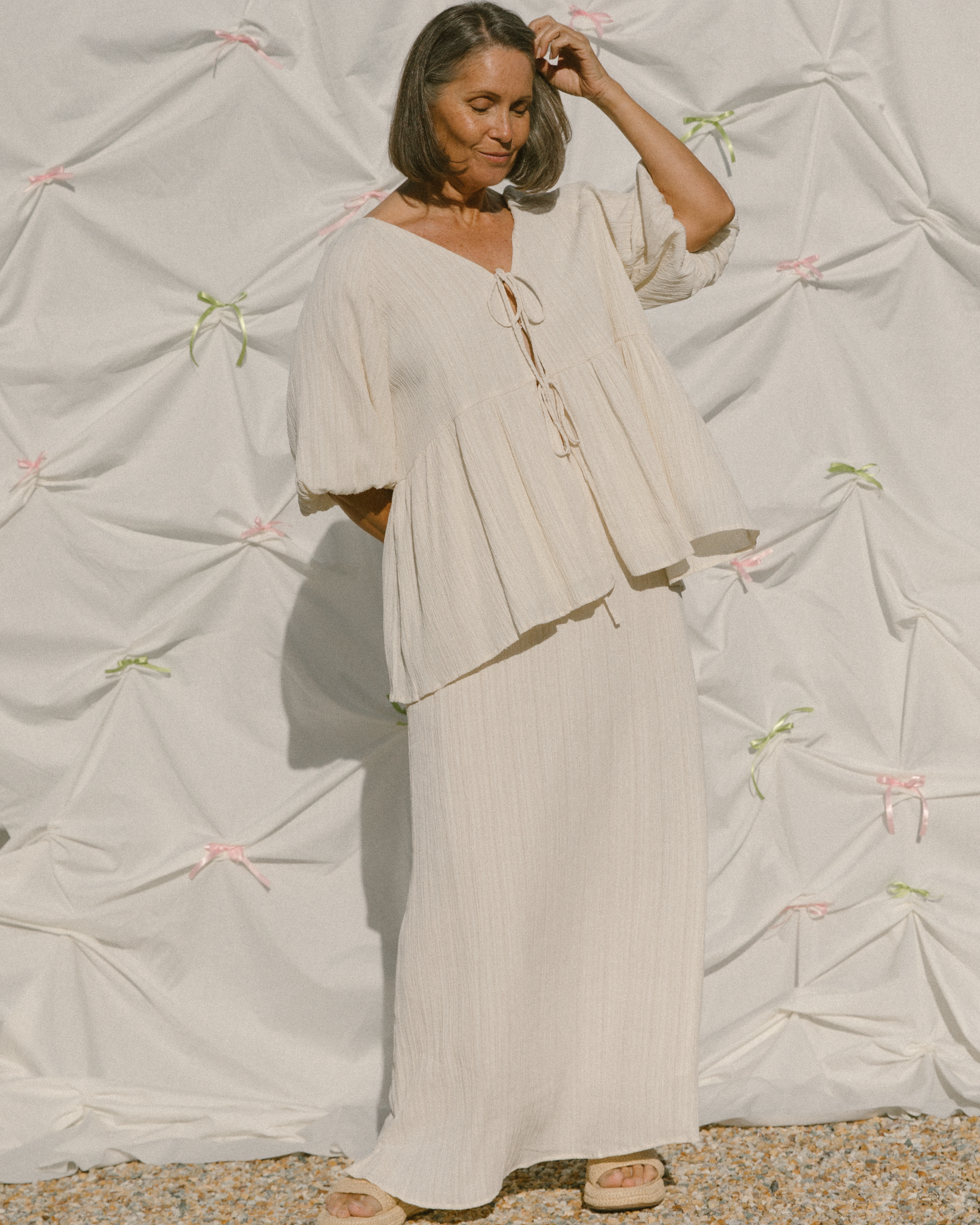 Woman wearing flowy cream outfit in a luxurious crepe fabric.