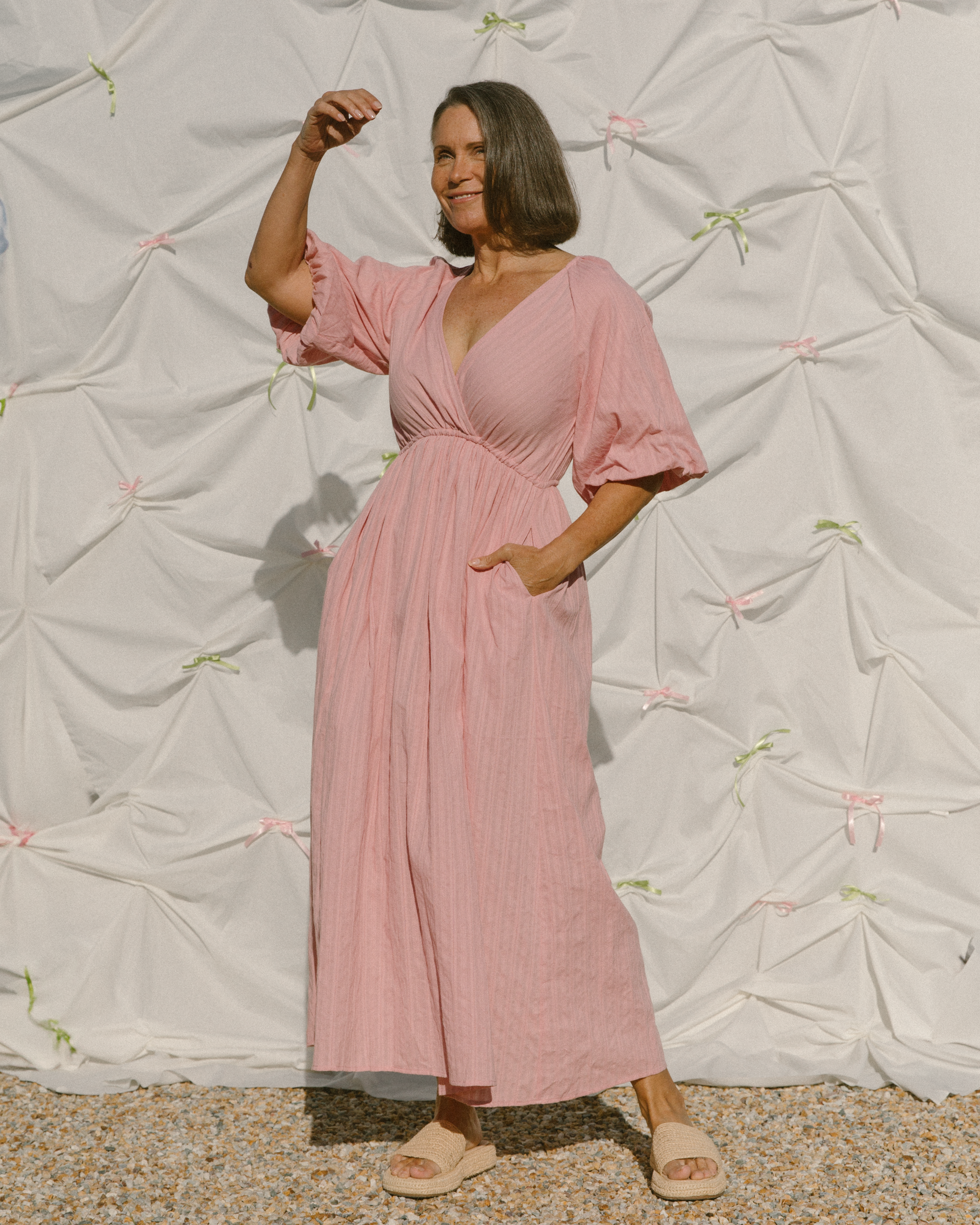 Woman in pink dress with billowing sleeves and cinch waist.