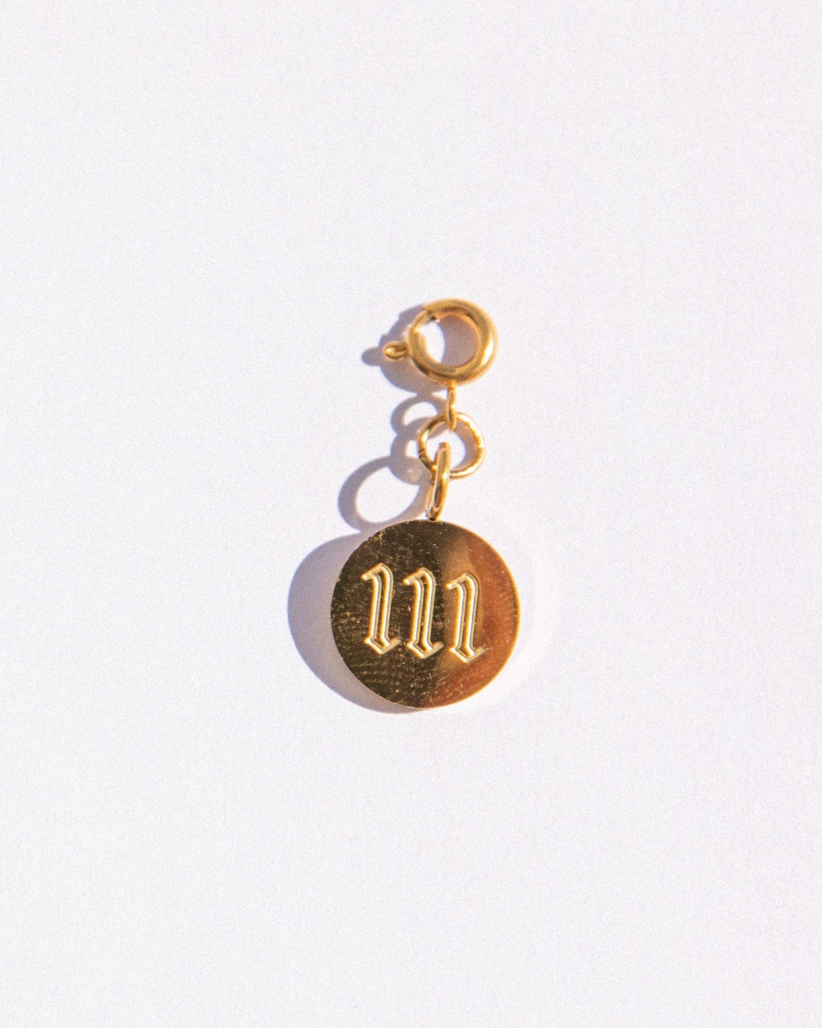 Gold circle charm with angel numbers '11' on a white background