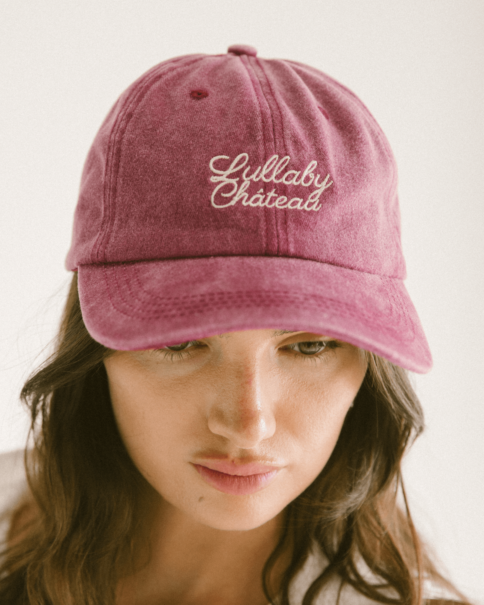 Women wearing a maroon cap with 'Lullaby Château' embroidery.