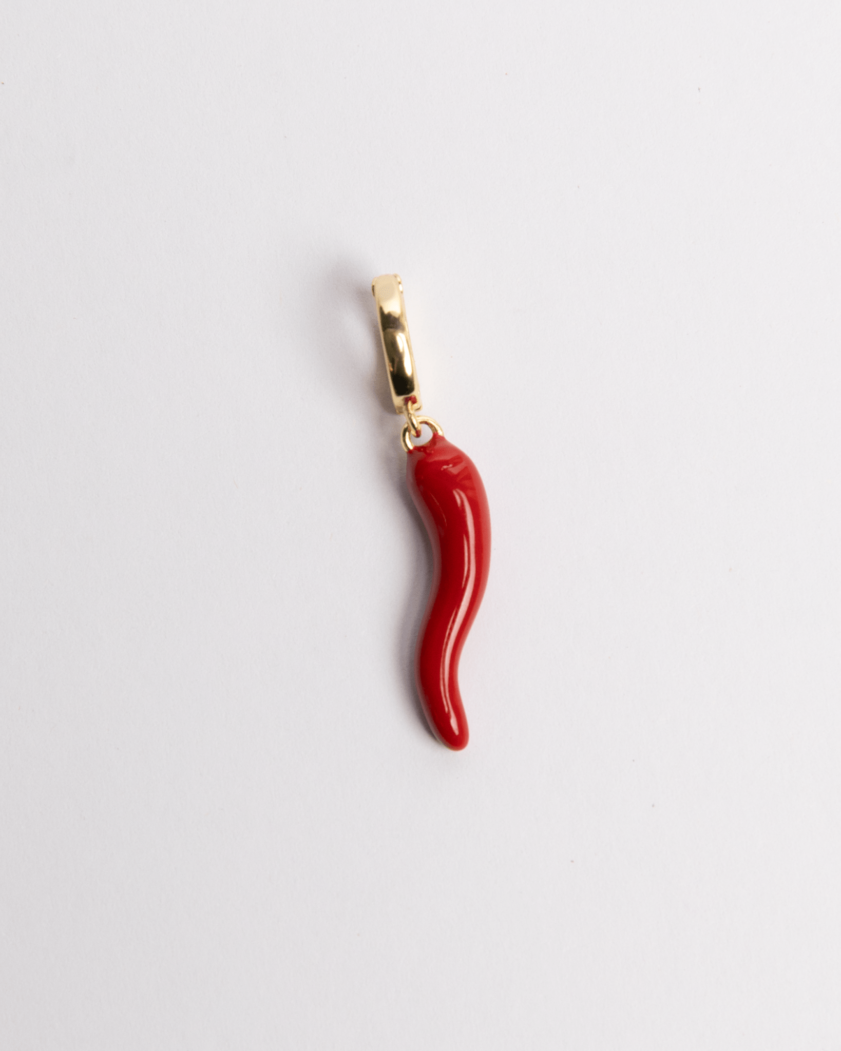 A red and gold-colored charm in the shape of a chili pepper with a gold clasp.