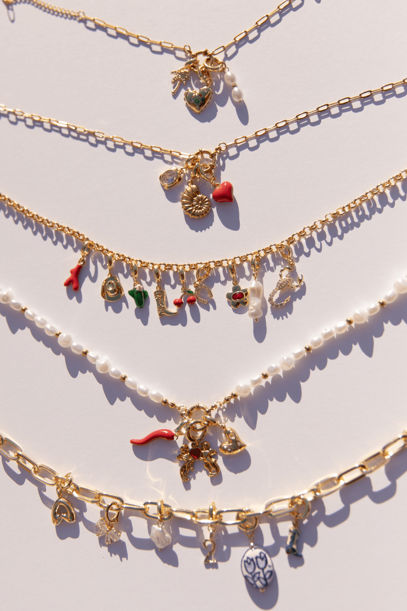 An assortment of stylish gold chain necklaces with charms attached.