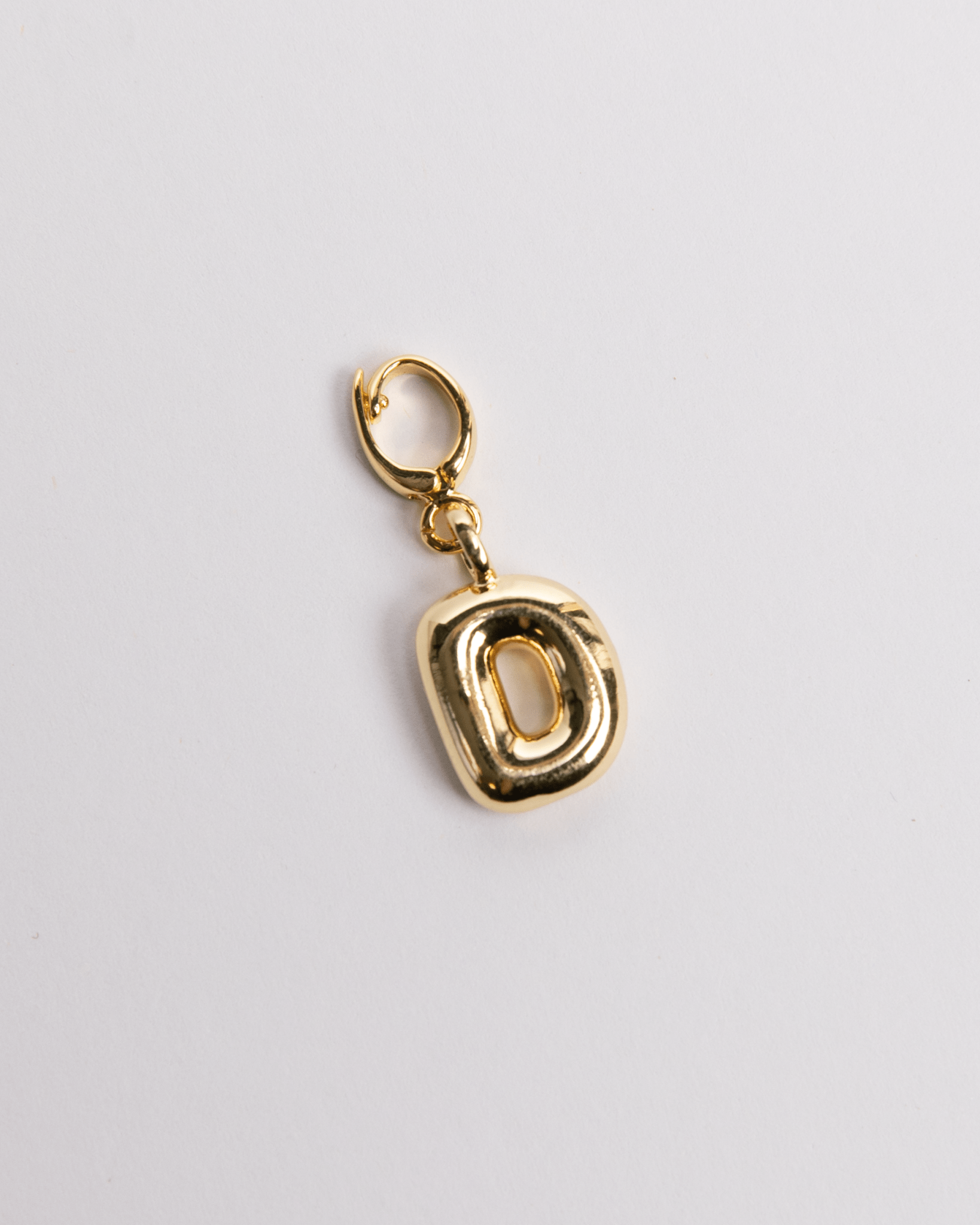 A gold-colored charm in the shape of the letter D with a secure clasp designed for attaching to necklaces or bracelets.