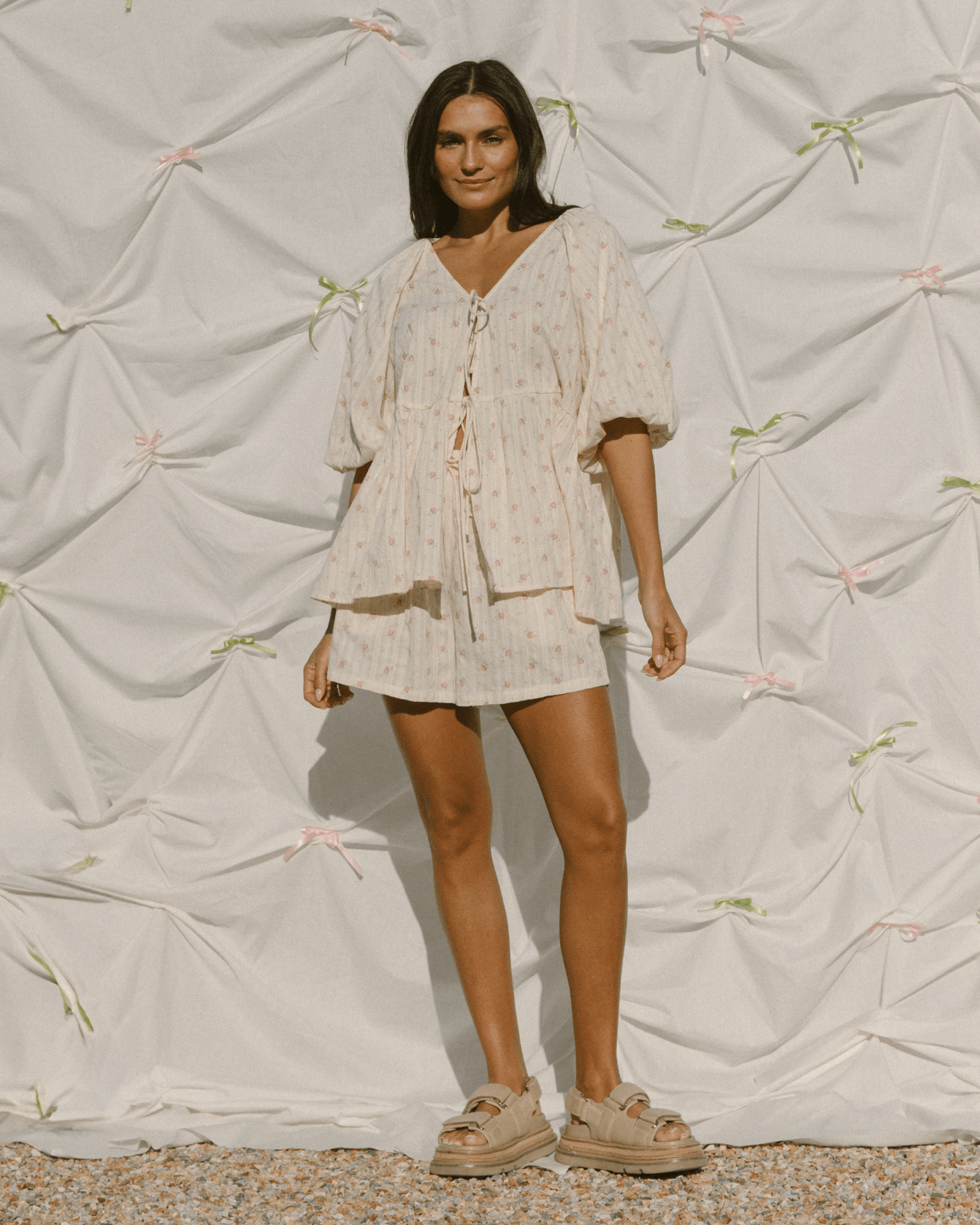 Woman wearing a light-colored outfit against a textured white background
