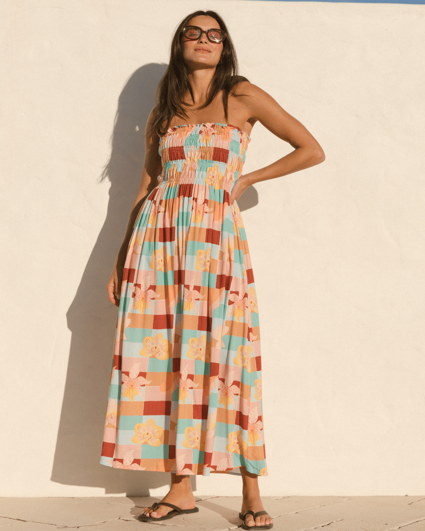 Woman wearing a strapless flowy spring dress with a multicoloured checkered floral print.