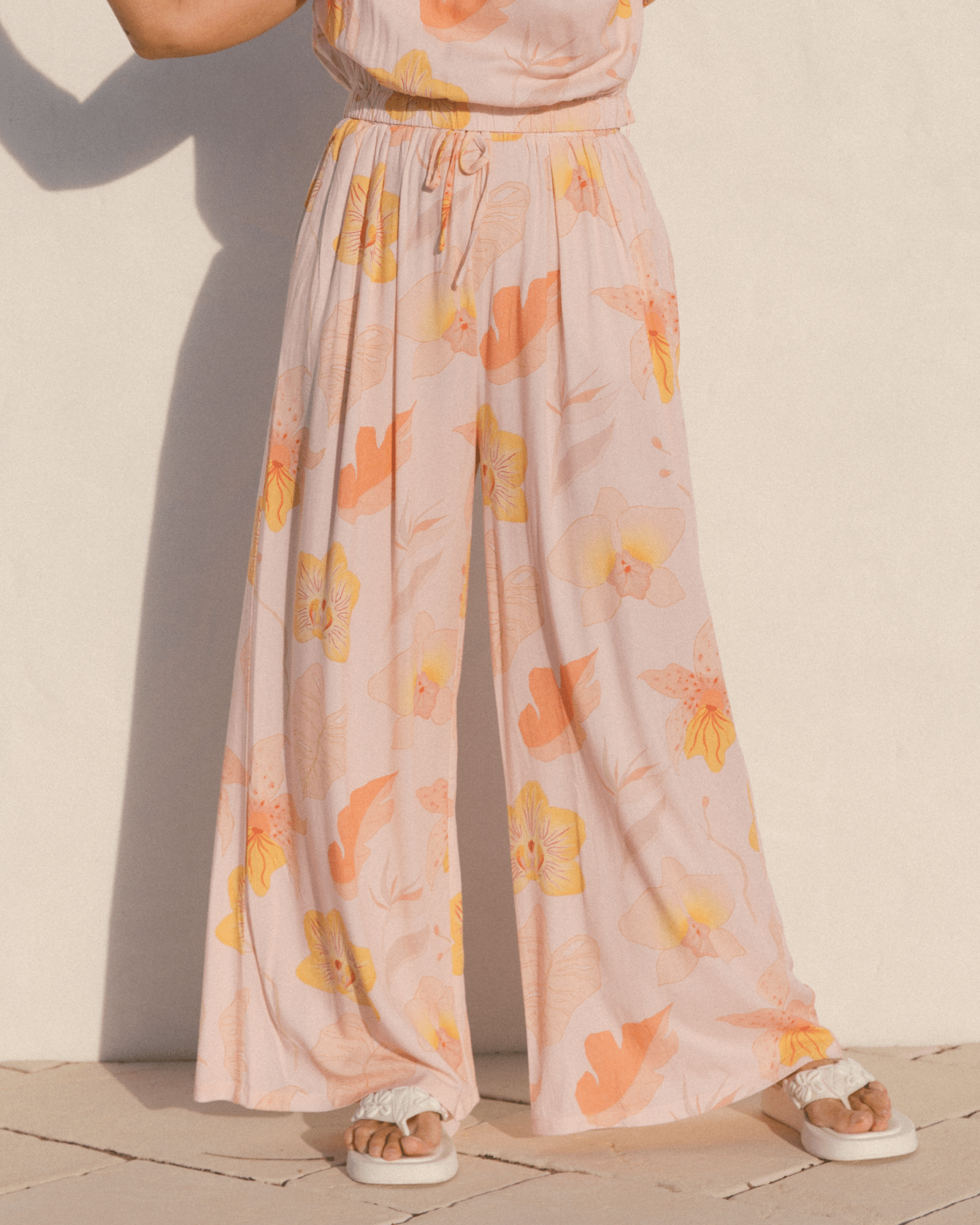 Woman wearing peach coloured floral pants.