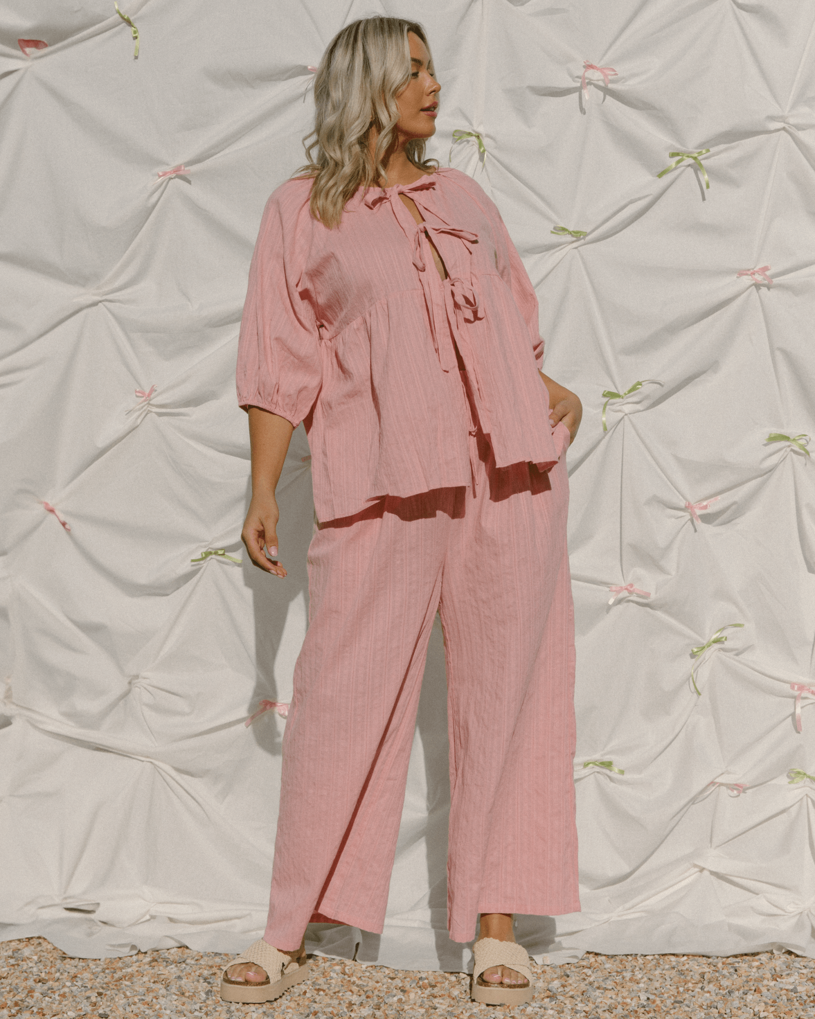 Woman wearing a pink outfit with a textured white background