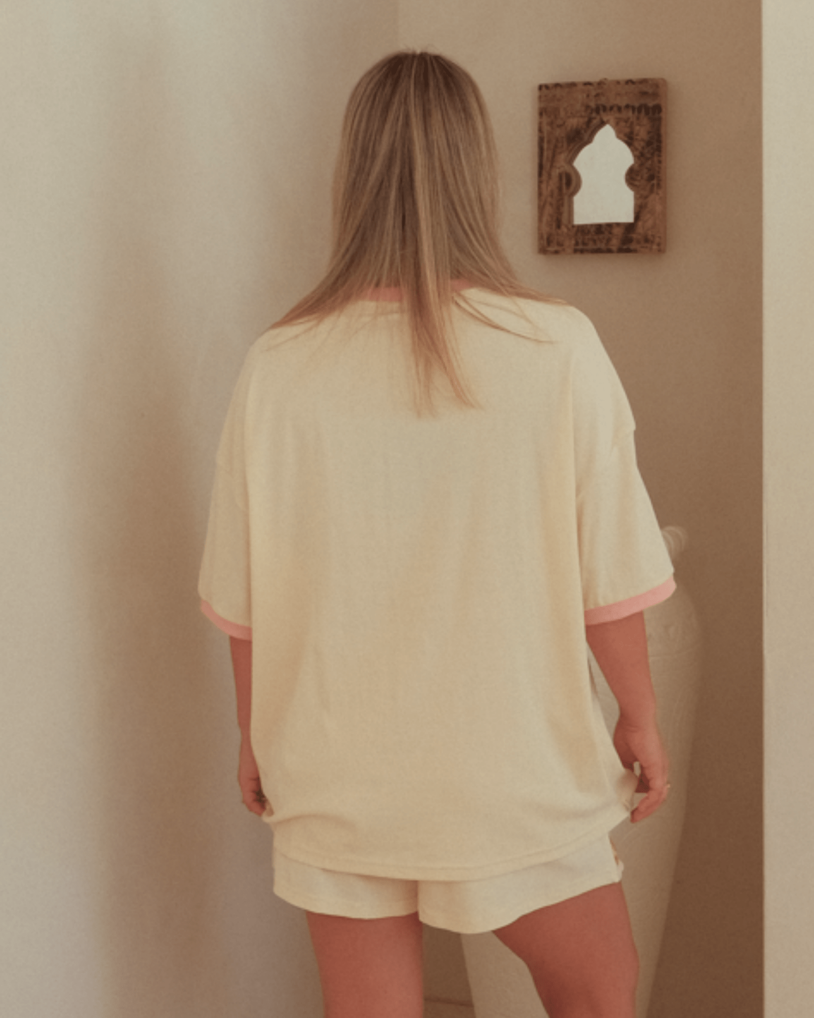 Woman wearing oversized beige loungeset with t-shirt and shorts.