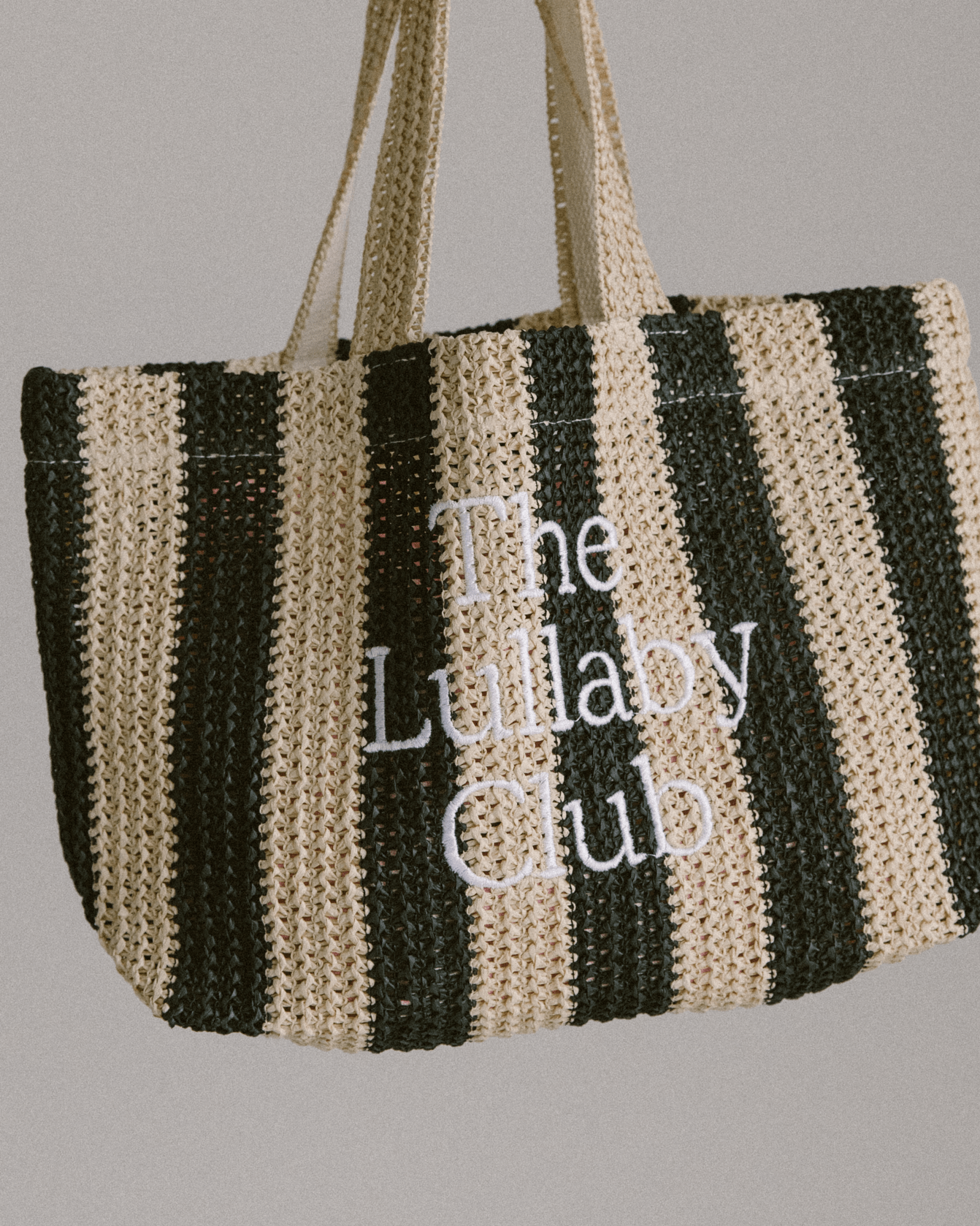 Raffia striped tote bag in black with The Lullaby Club embroidered on the front.