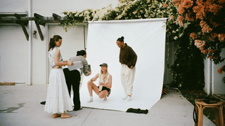 Models posing on backdrop in tracksuit collection, winter essentials behind the scenes with photographer and stylist.