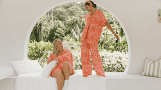 Two women standing on ledge, wearing christmas pink and red pyjamas