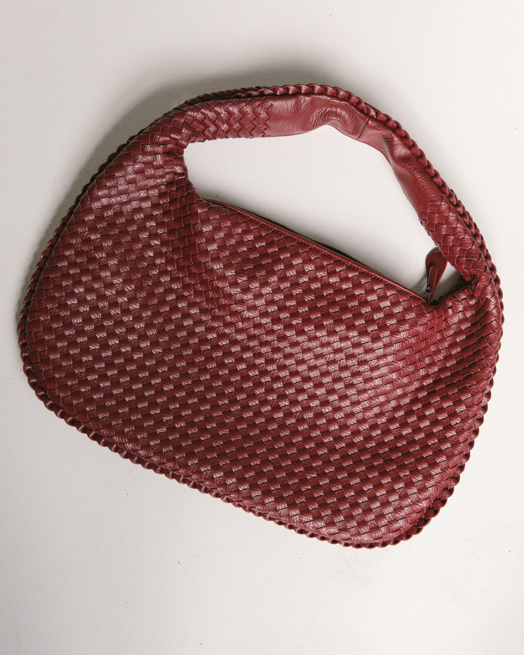 Close up of leather-look deep red woven bag.