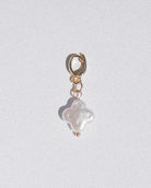 Gold charm with a white pearl on a light gray background