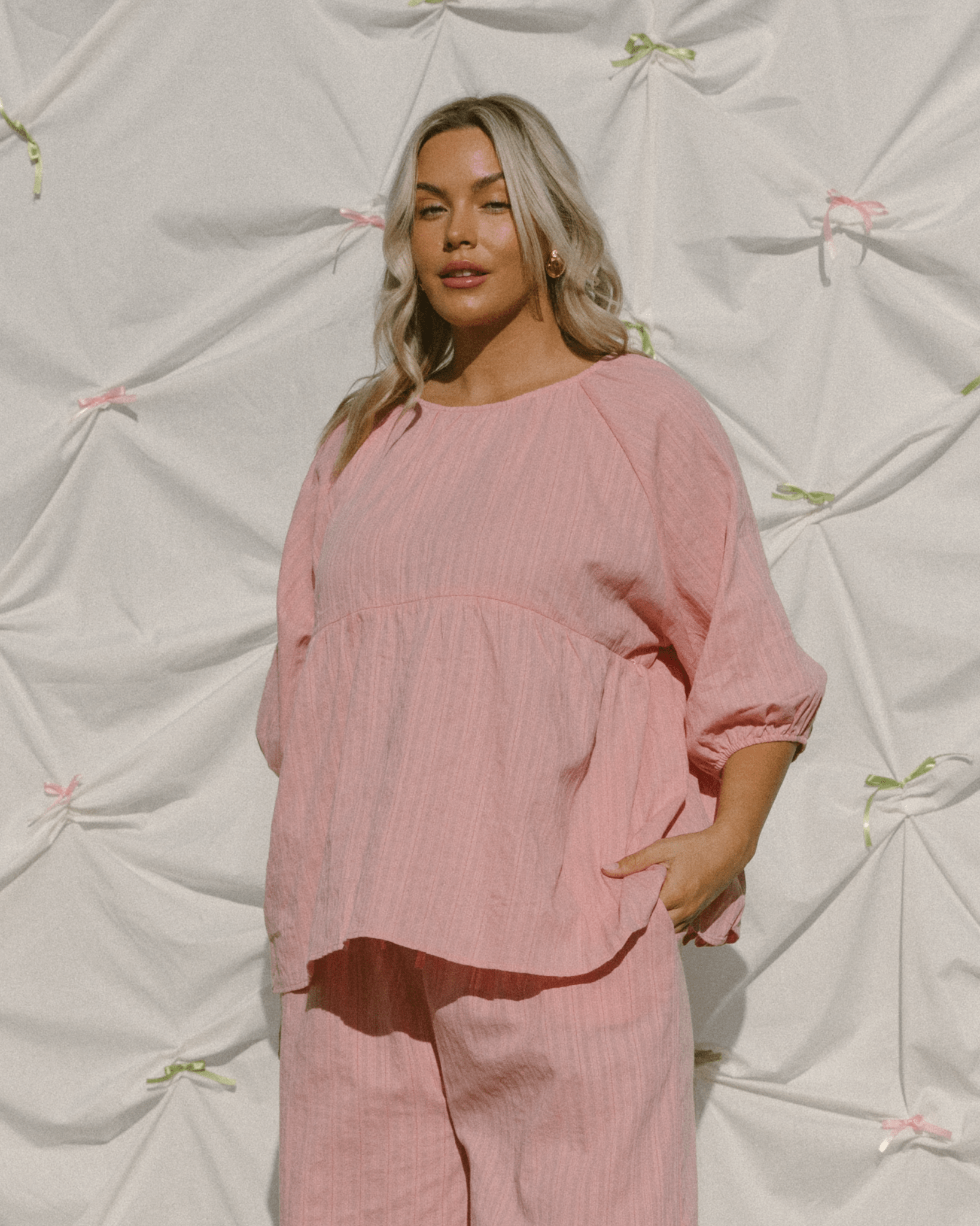 Woman wearing reversible pink top with breastfeeding hidden zippers. 