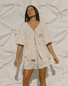 Woman wearing cottage core inspired outfit in a cream and pink flower pattern. 