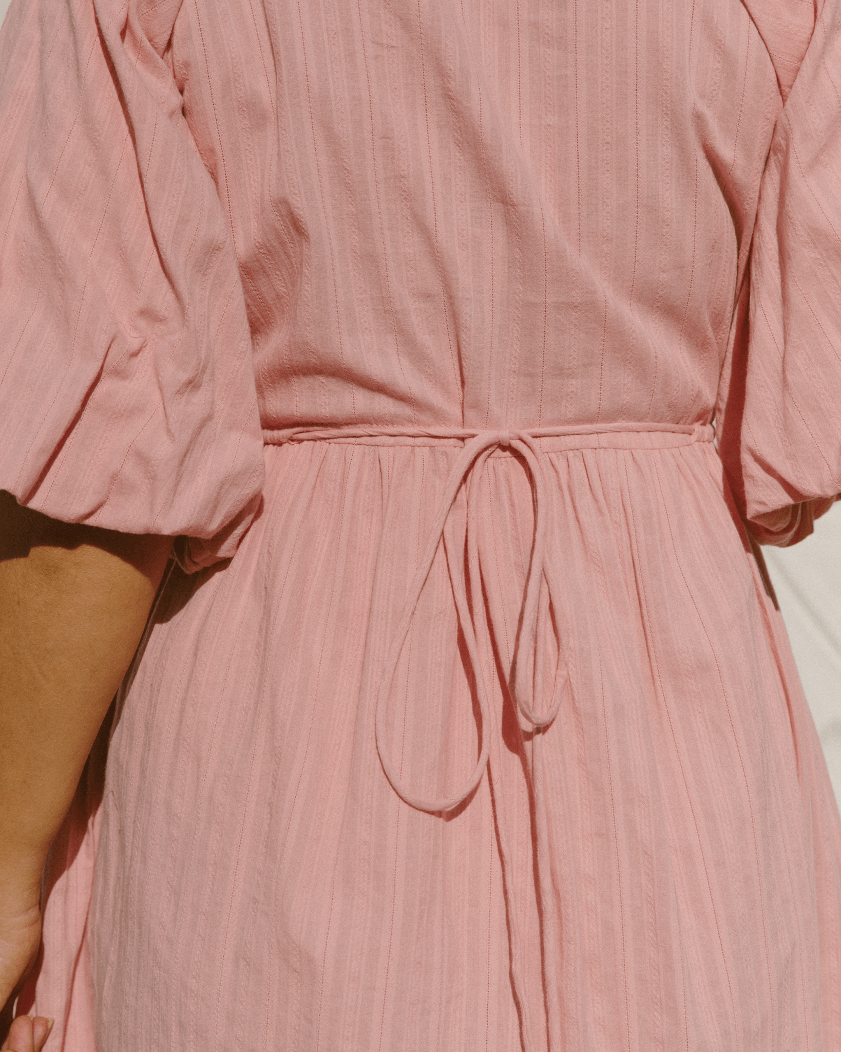 Close-up of tie-up back on pink maxi dress. 