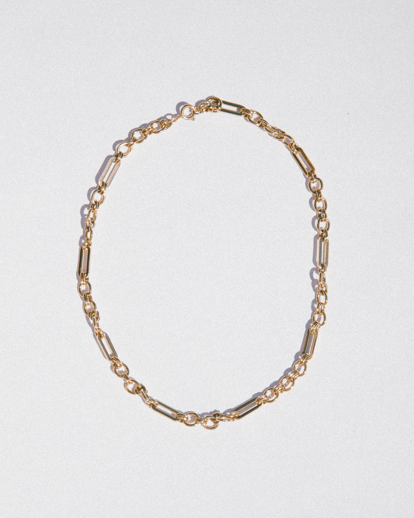 Gold chain necklace on a light gray background