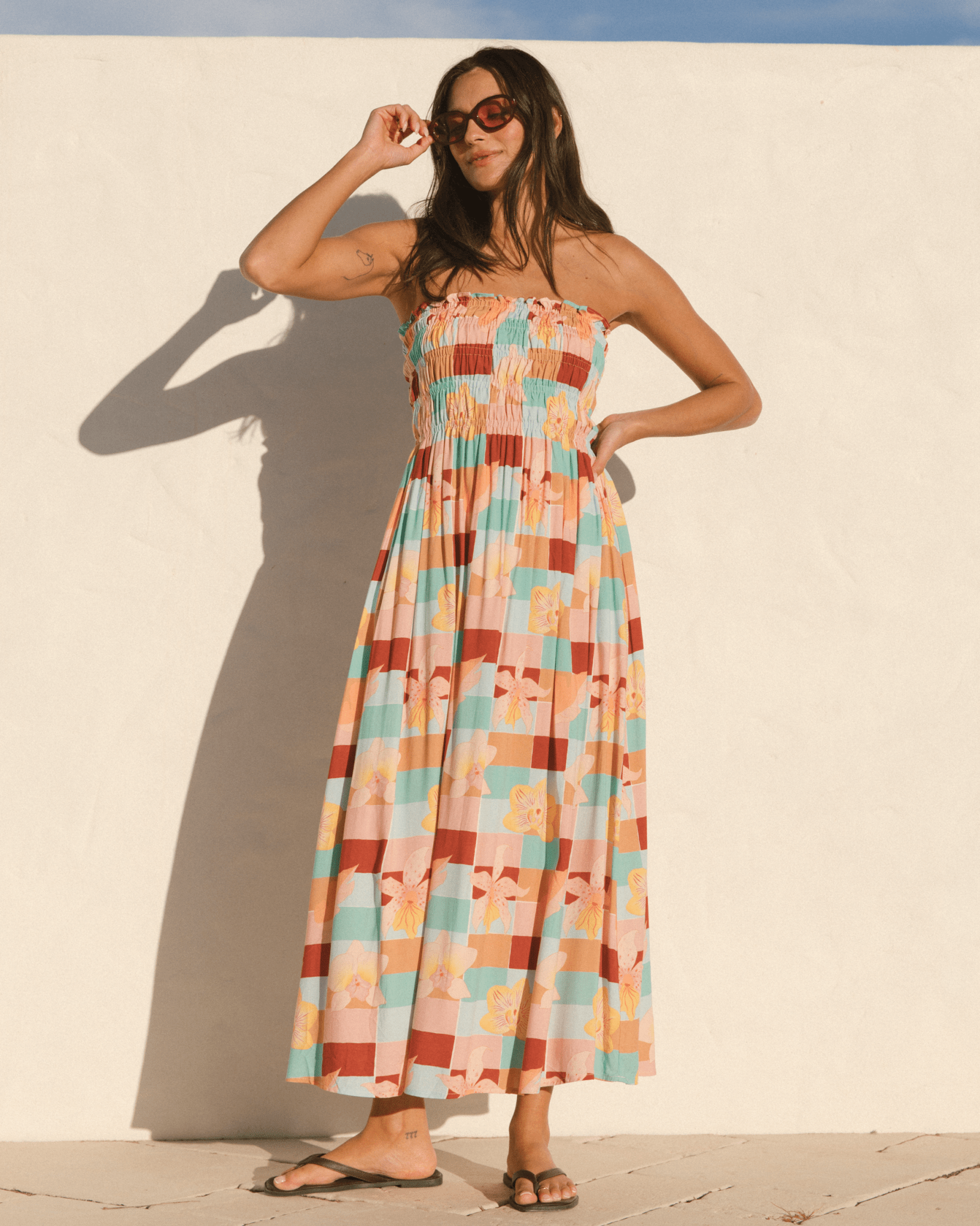 Woman wearing a shirred body strapless dress with a flowy skirt. 