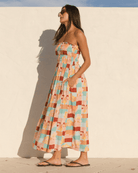 Woman wearing a colorful checkered dress against a white wall