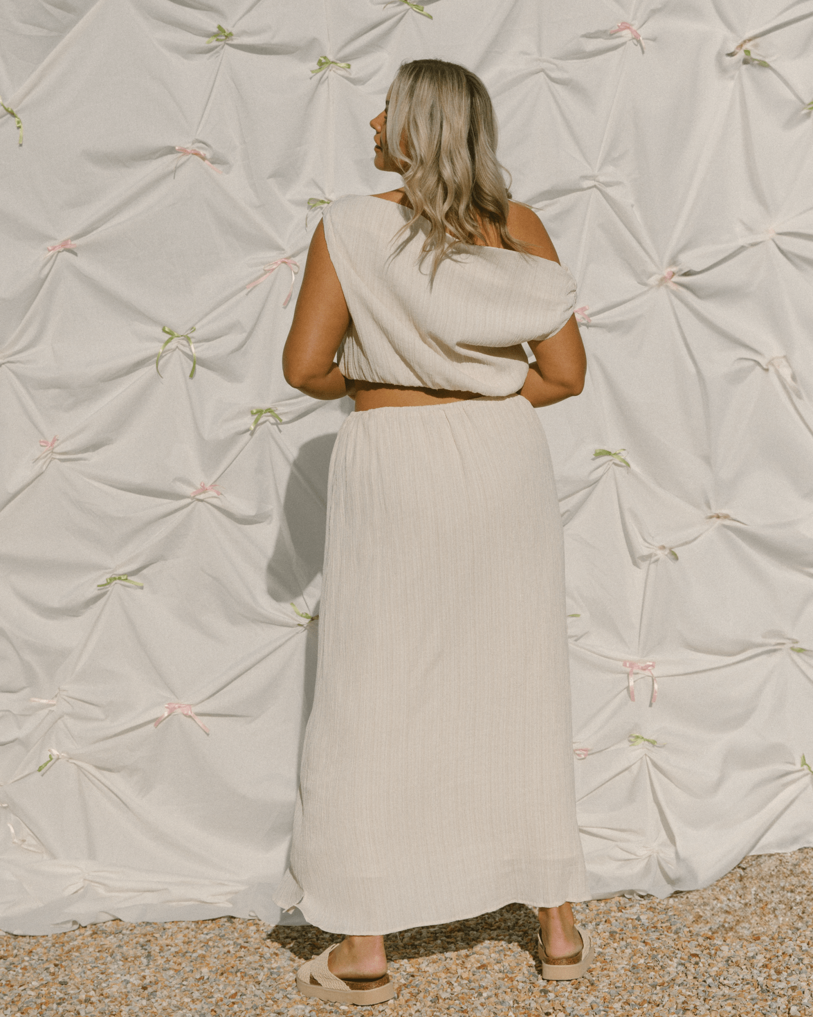 Woman wearing matching crop top and skirt set in a cream crepe fabric. 