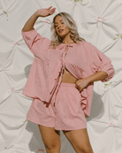 Woman wearing blush pink matching outift with flowy shirt and matching shorts. 