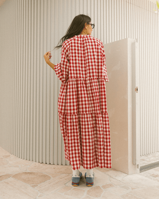 Woman in flowy postpartum-friendly maxi dress in red gingham