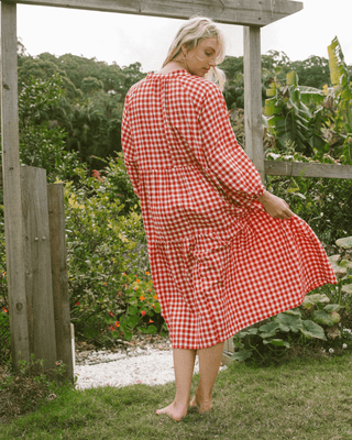 Woman in flowy postpartum-friendly maxi dress in red gingham