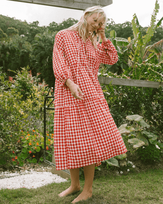 Woman in flowy postpartum-friendly maxi dress in red gingham