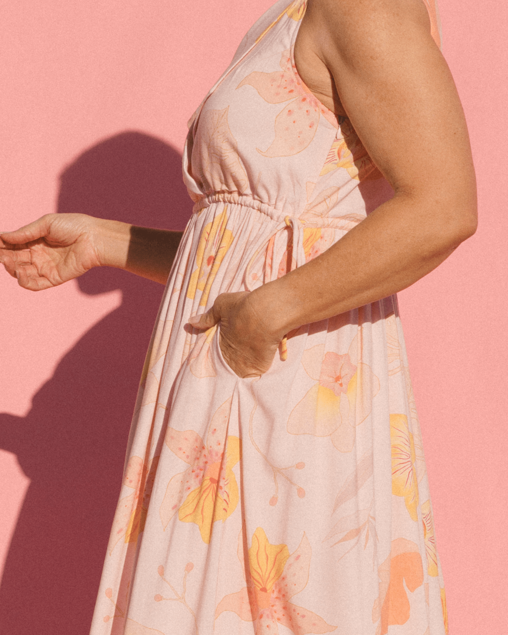 Woman wearing light pink maxi dress with side seam pockets and adjustable drawstring waist
