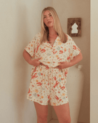 Woman wearing a pattern pajama set in a room with a mirror on the wall.