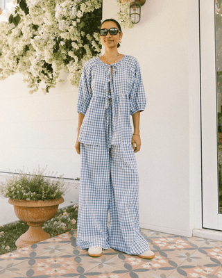 Woman wearing The Lullaby Club Posey Pants in Blue Gingham, featuring a relaxed, oversized fit with an elastic waistband and functional drawstring