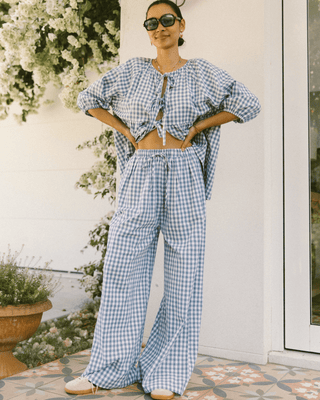 Woman wearing The Lullaby Club Posey Pants in Blue Gingham, featuring a relaxed, oversized fit with an elastic waistband and functional drawstring