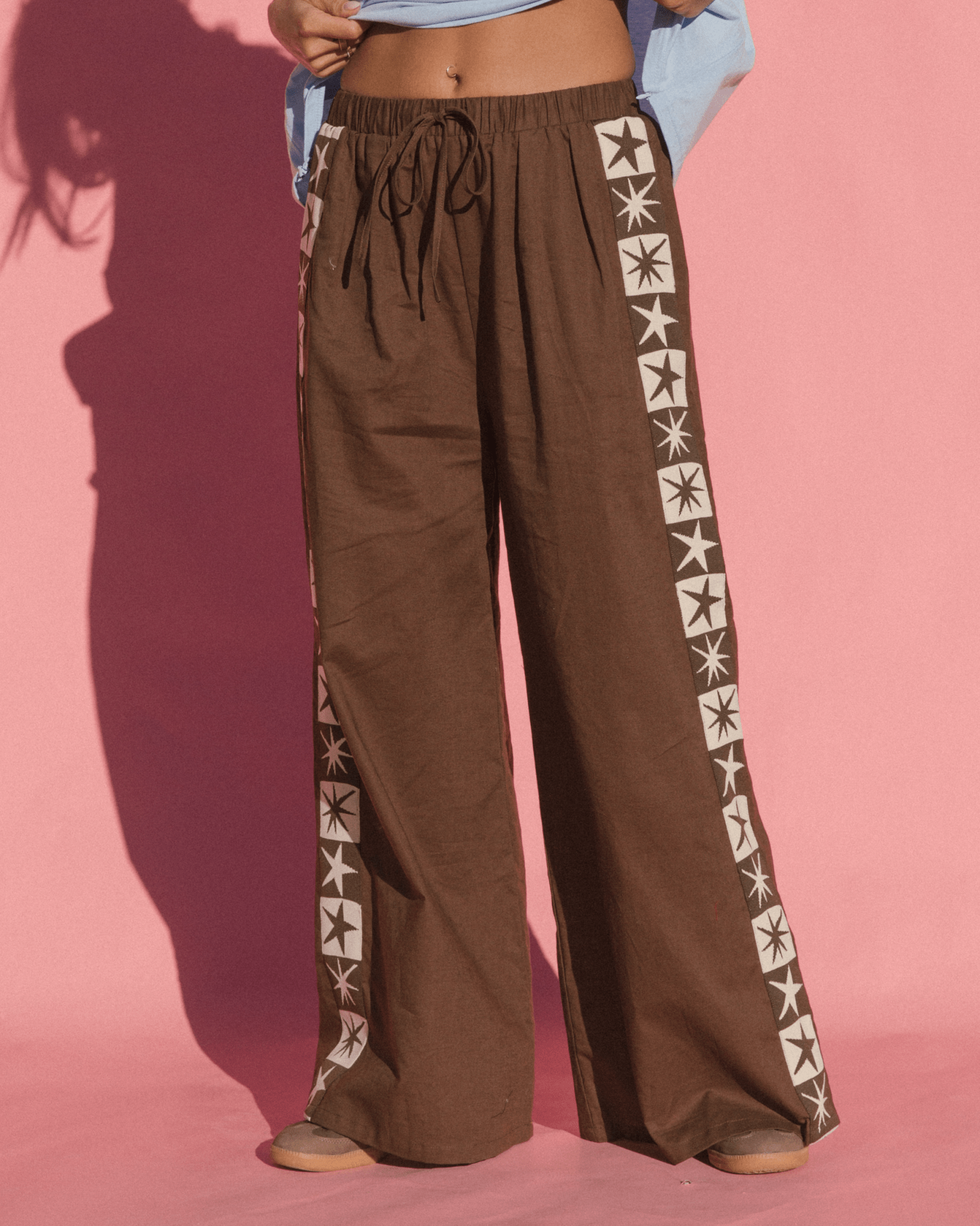 Brown cotton wide-leg pants with adjustable elastic waistband and knit star contrast detailing down the side-seam.