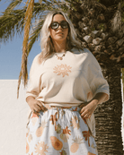 Relaxed women wearing beige coloured relaxed t-shirt with idyllic sun print on front with breastfeeding zippers & blue summer print relaxed lounge pants with drawstring waist