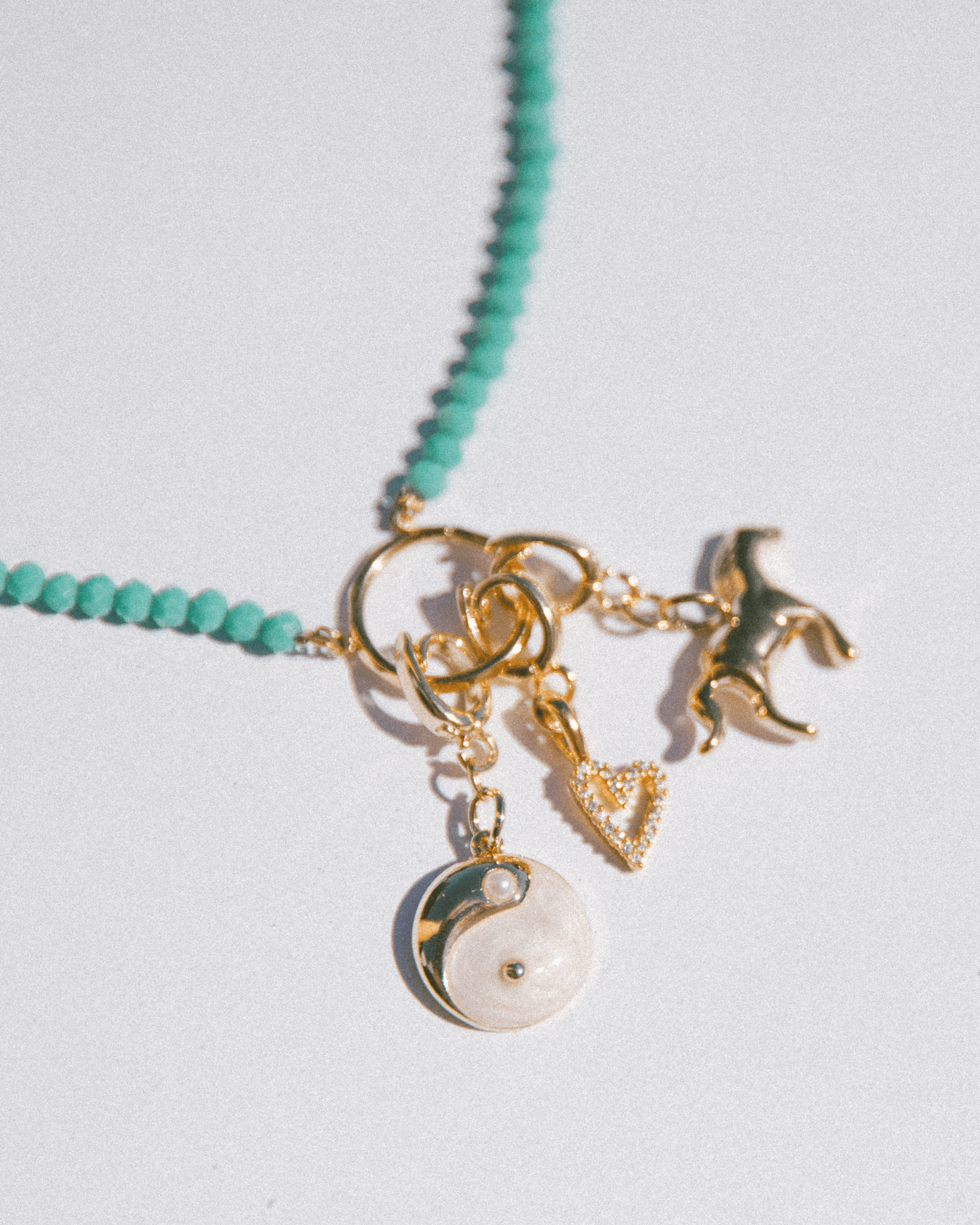 Necklace with gold and green charms on a light gray background