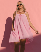 Woman wearing a pink swing dress against a pink background
