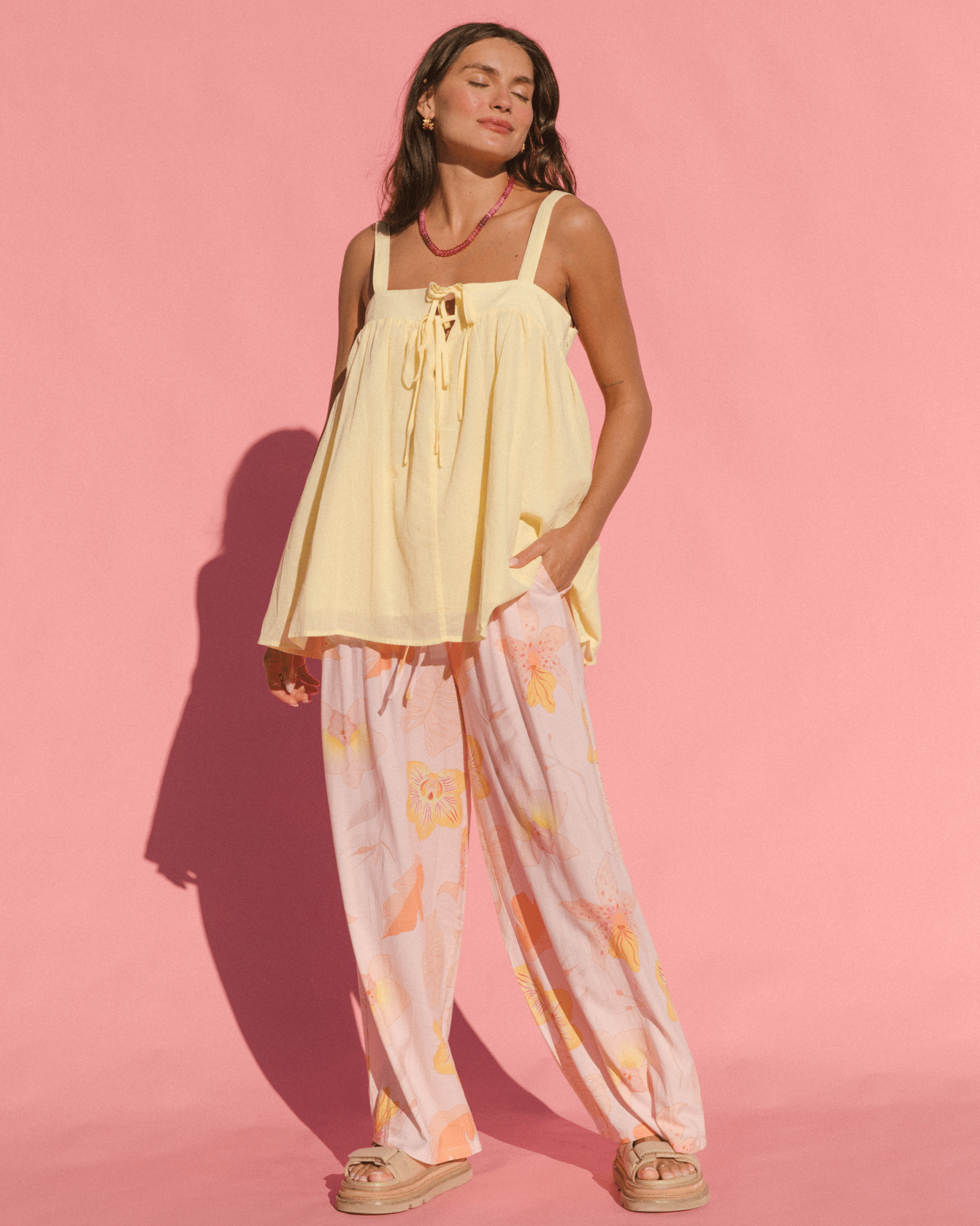 Women wearing stylish summer outfit with flowy bright yellow breathable top and lightweight floral pink long pants