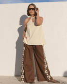 Women wearing butter yellow cotton halter top and brown linen pants with star detailing down the side. 